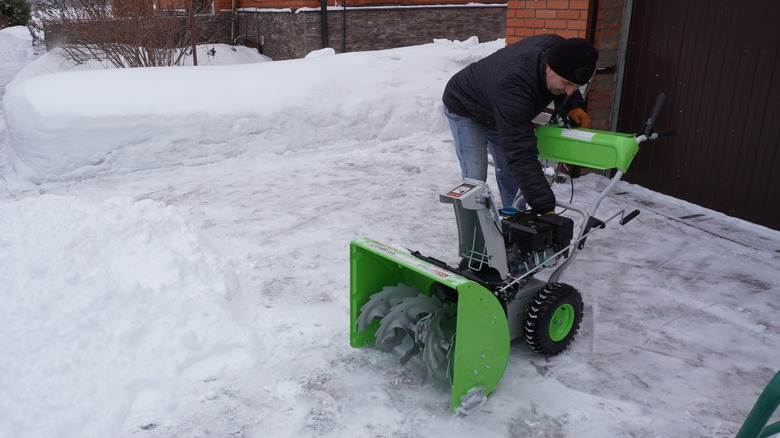 Mann prøver å starte en snøfreser