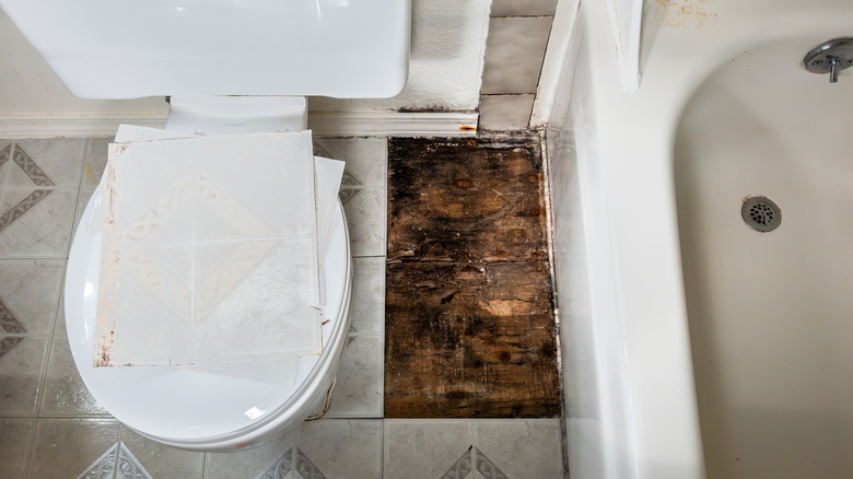 Mugget treverk under fliser på bad mellom toalett og badekar