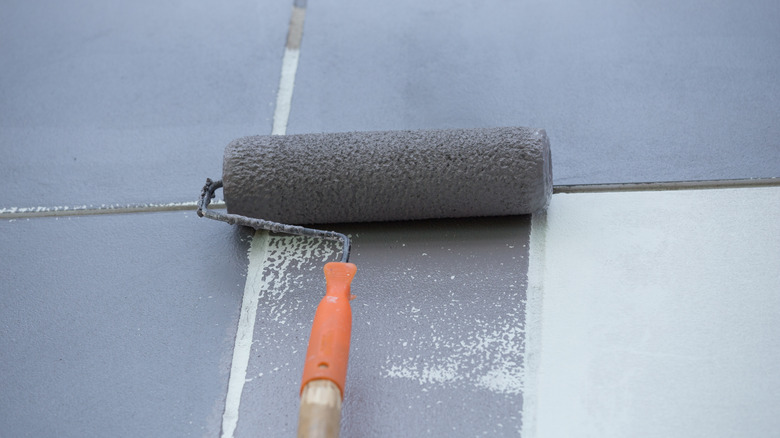 Rullende grå maling på hvitt flisgulv