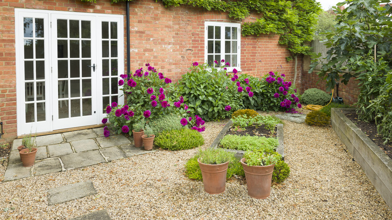 Murhus med hagelandskap og blomstrende busker.