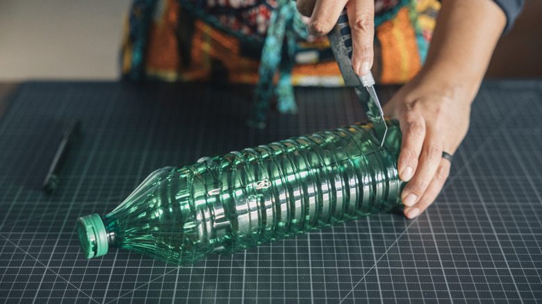 Person som kutter en plastflaske med en verktøykniv.