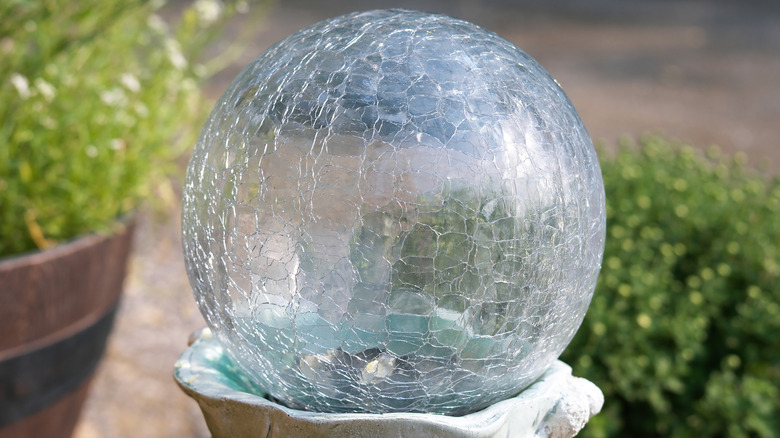 Klar, krakelert glasskule på toppen av betongsokkel.