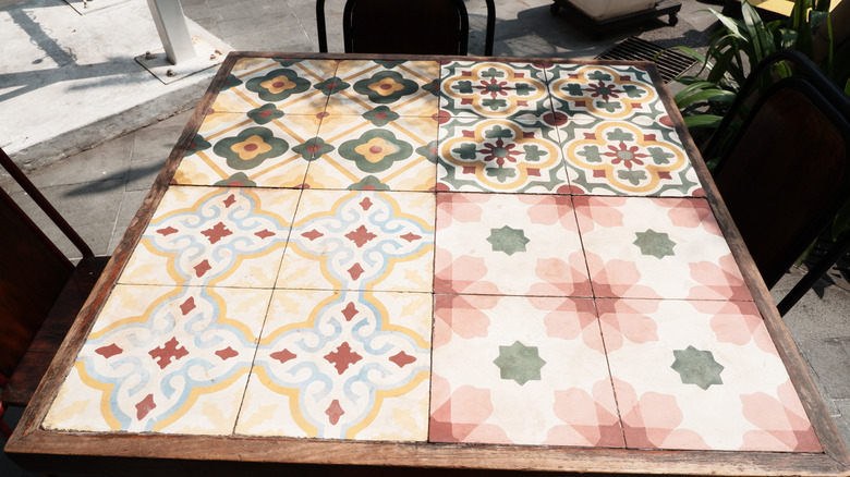 Et kvadratisk flislagt trebord ute på en asfaltert uteplass.