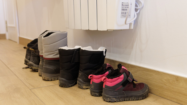 En serie sko under en radiator, men som ikke berører den direkte, for å tørke.