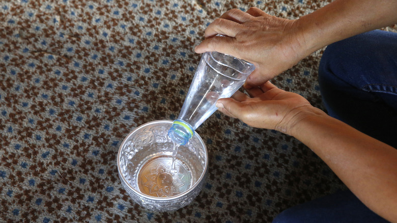 person som heller vann i en liten beholder