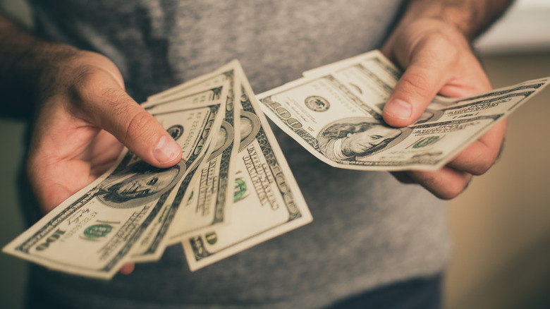 Mann som holder dollarsedler i begge hender og teller dem