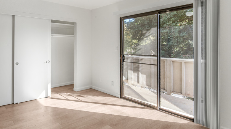 En skyvedør i glass med bekledning åpnet med direkte lys som strømmer inn på gulvet og deler av veggen