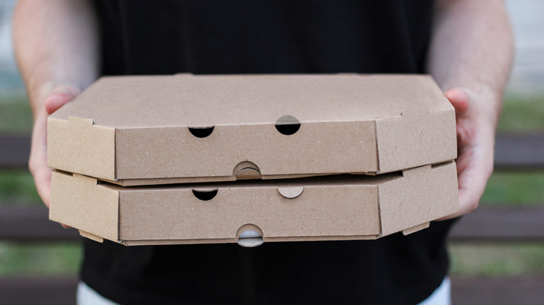 En person som holder to vanlige pizzaesker