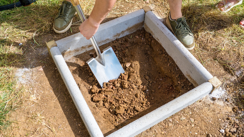 person som bruker spade med jord i hevet hagebed