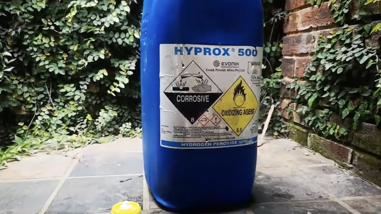 En flaske med 50 % konsentrasjon av hydrogenperoksid på en flislagt terrasse.