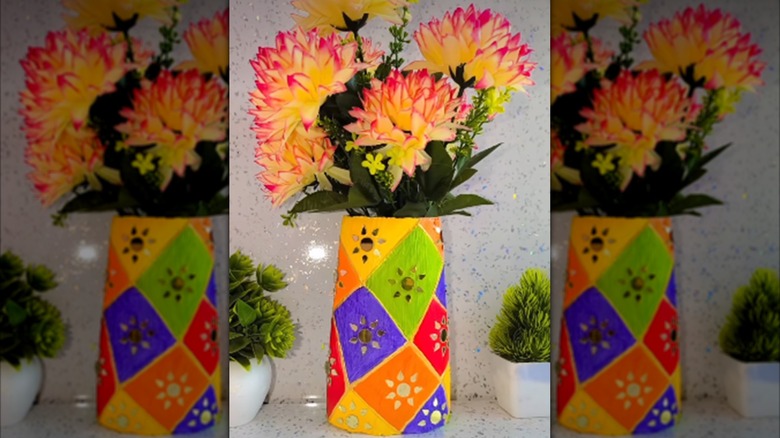 En benkevase laget av en malt sjampoflaske er fylt med falske blomster.
