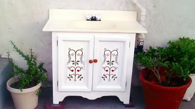 En hvit, vintage stil forfengelighet laget av et gammelt skap med et vakkert malt design på forsiden