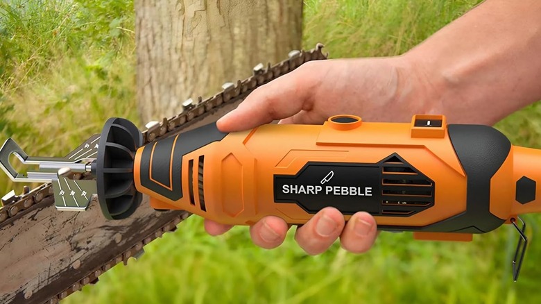En hånd som holder Sharp Pebble motorsagsliperen