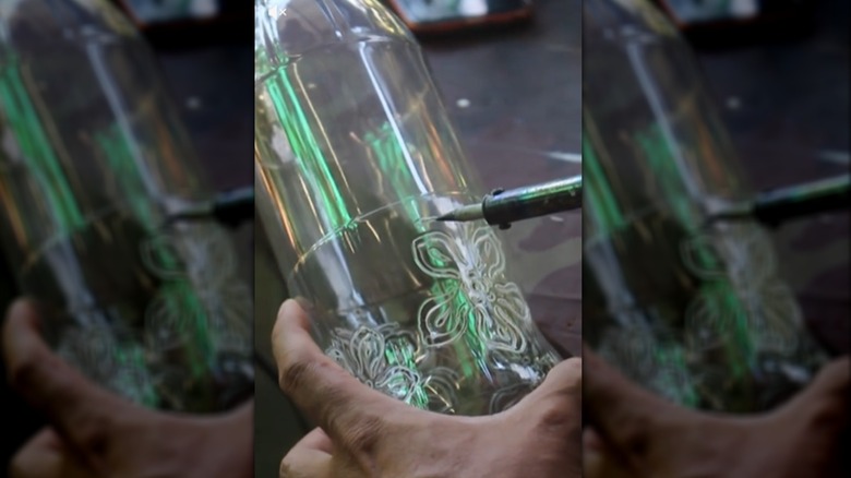 En person som bruker en loddebolt på plastflaske for design